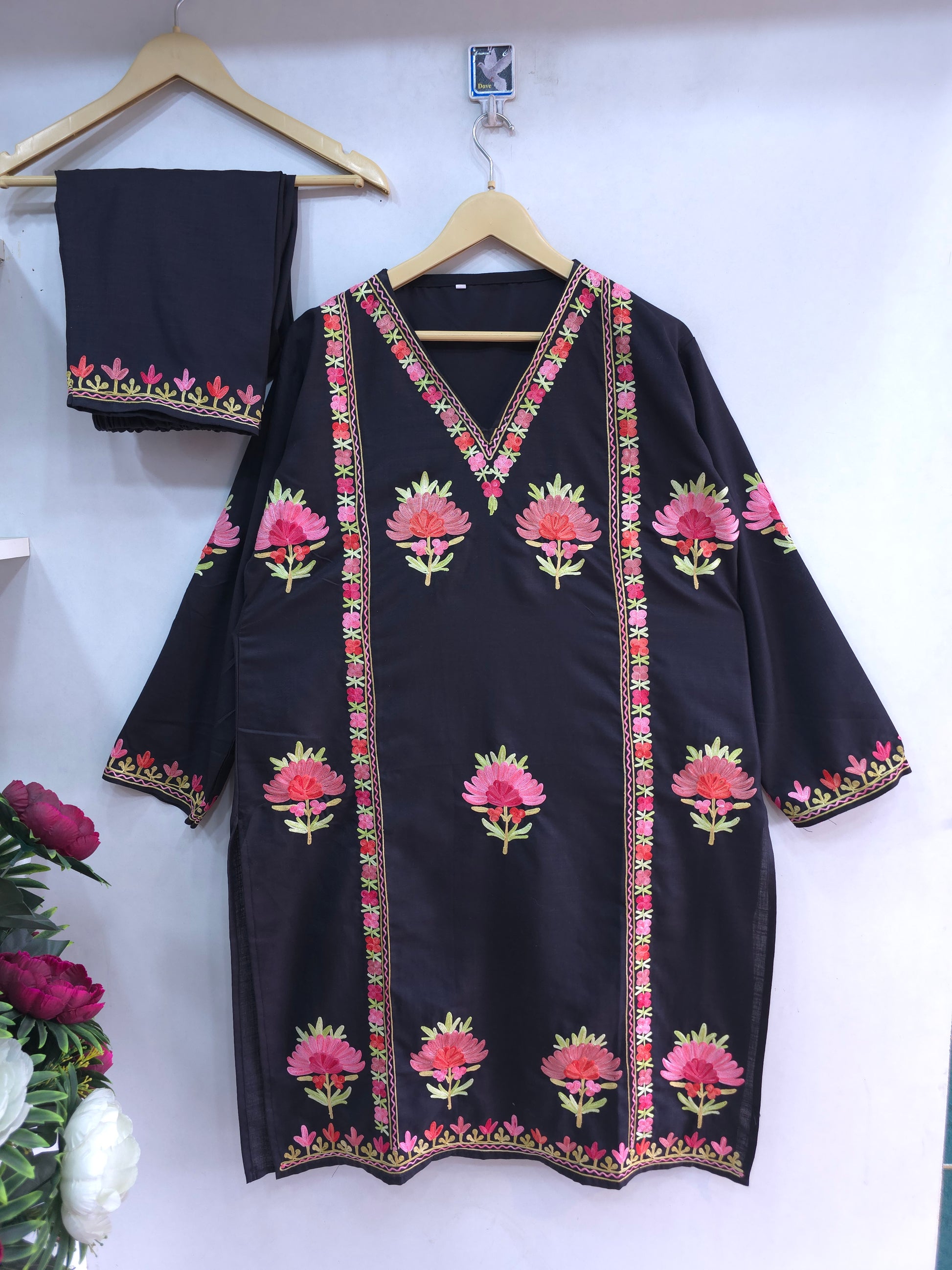 Black traditional outfit with floral embroidery on a white background